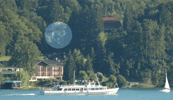 Blick vom See auf das bewaldete Südufer, die Lage der Pension ist markiert