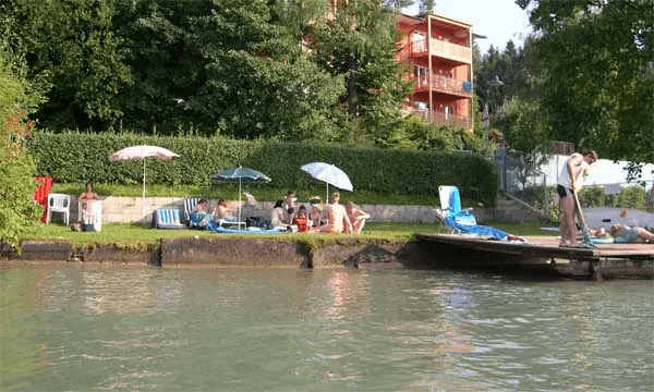 Liegewiese mit Sonnenschirmen und Holzsteg am Wörthersee