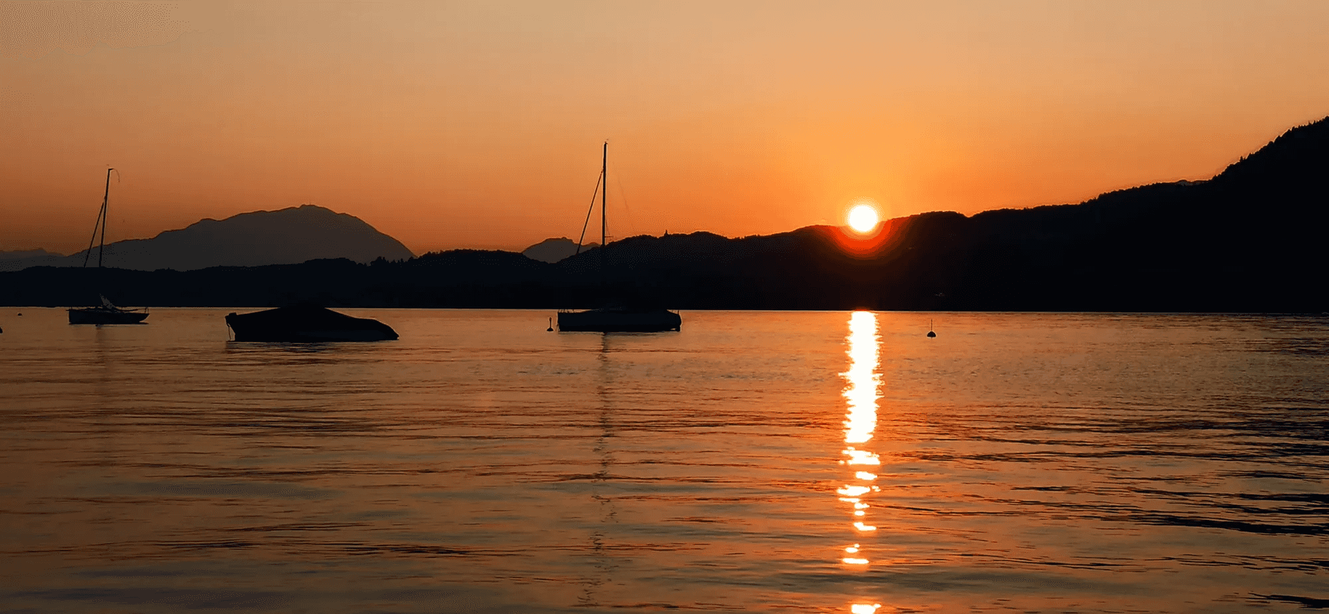 Sonnenuntergang über dem Wörthersee mit Booten in Ufernähe